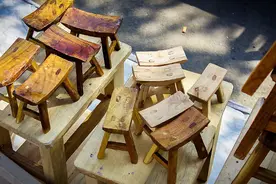 农民大哥街边卖板凳，10块钱一张大小任选，很多人选小的不要大的图片