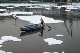 印度被污染河流漂浮白色泡沫 渔民划船似在“云海翱翔”图片