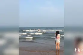 青岛石老人海水浴场，洋小伙顶着大浪洗海澡，美女一旁拍照