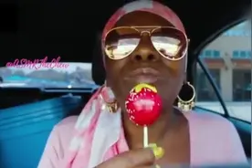 非洲大妈吃棒棒糖, 舌头和手指都染红了, 不过看起来津津有味。