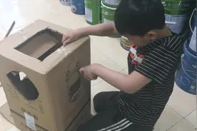 小明用纸箱做机器人盔甲，还自称有攻击力。妹妹玩的很开心