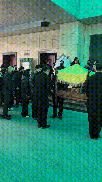 许何弯着腰抱着何晴遗像，背影很难过，许亚军没来给何晴撑伞！