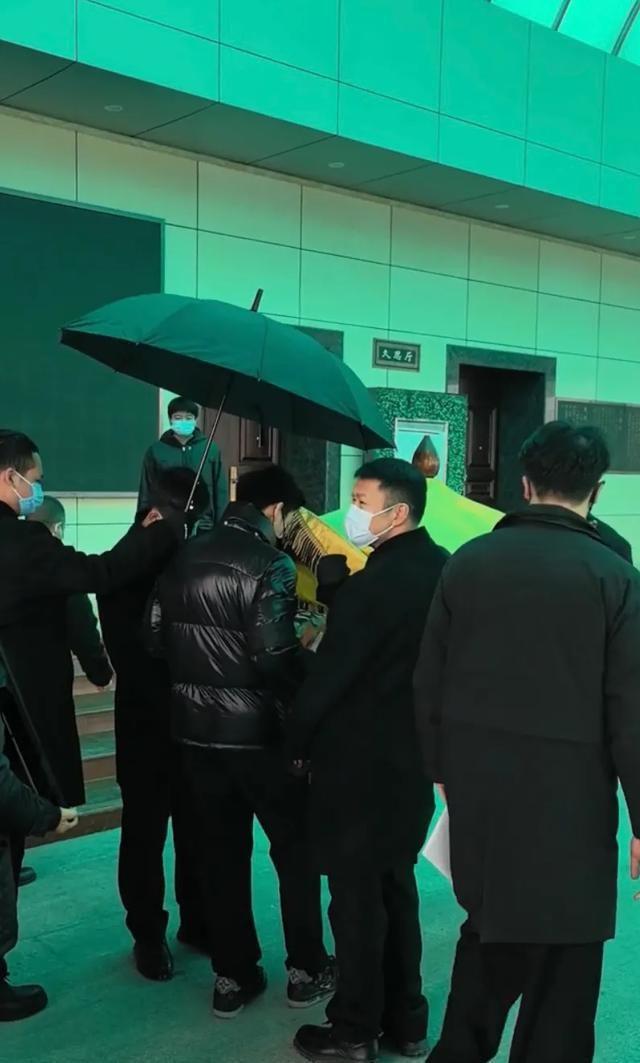 许何弯着腰抱着何晴遗像，背影很难过，许亚军没来给何晴撑伞！