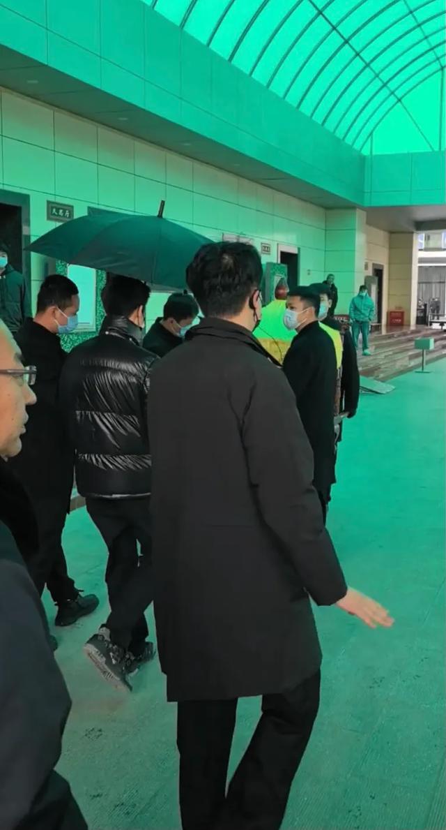 许何弯着腰抱着何晴遗像，背影很难过，许亚军没来给何晴撑伞！