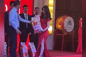 公司年会礼仪小姐穿红色开衩裙踩高跟鞋吃力颁发大米，拍摄者：扛起的是生活，每份岗位都有每份岗位的不容易图片