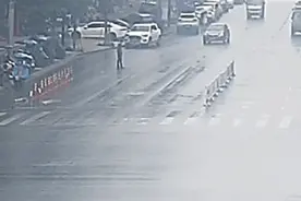 雨天，男子蹲在马路中央，警车缓缓靠近……图片